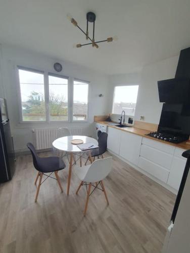 een keuken met een tafel en stoelen in een kamer bij Charmant appartement avec vue mer in Cherbourg en Cotentin