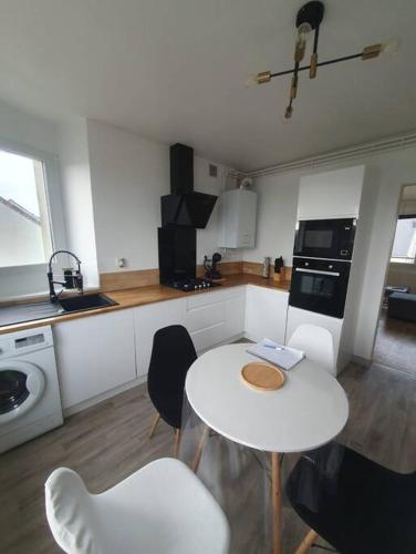 eine Küche mit einem weißen Tisch und Stühlen in der Unterkunft Charmant appartement avec vue mer in Cherbourg en Cotentin