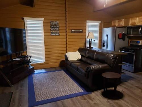 sala de estar con sofá de cuero y nevera en Beaver Lake Arkansas Luxury Cabin, en Rogers