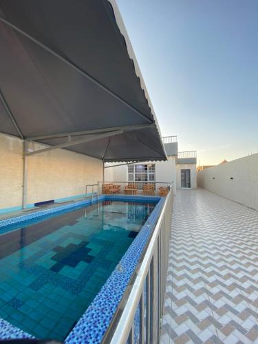 ein Pool mit einem Sonnenschirm auf einem Gebäude in der Unterkunft شاليهات ملك in Rafha