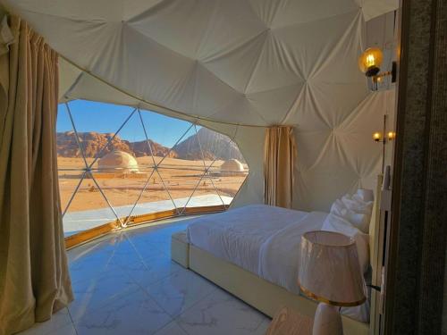 a bedroom with a bed and a view of the desert at Wadi rum anwar luxury camp in Wadi Rum