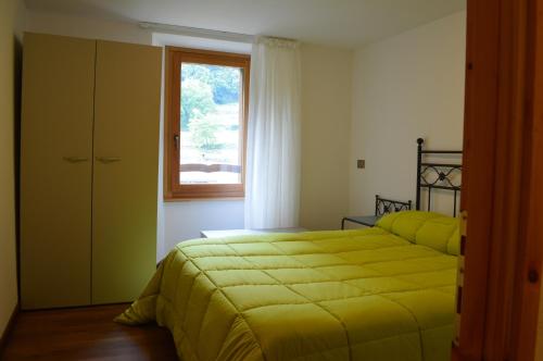 - une chambre avec un lit jaune et une fenêtre dans l'établissement B&B Il Paradiso Mozzio, à Mozzio