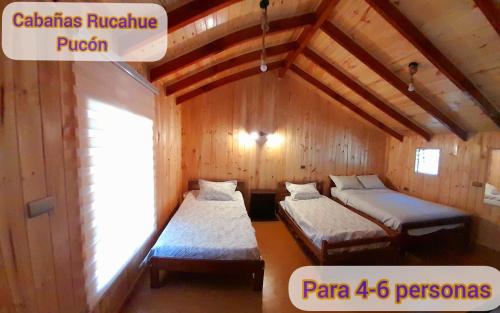 Habitación con 2 camas en una cabaña de madera en Cabañas Rucahue, en Pucón
