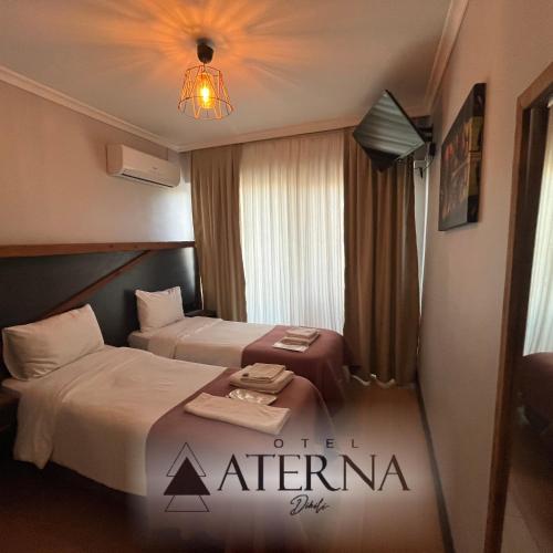 Habitación de hotel con 2 camas y lámpara de araña. en ATERNA HOTEL, en Dikili