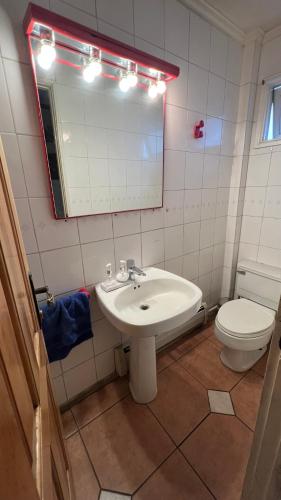 a bathroom with a sink and a toilet and a mirror at Anoka House in Punta Arenas