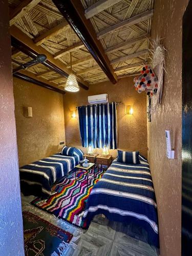 two beds sitting in a room with a rug at Riad Tamdakhte in Aït Ben Haddou