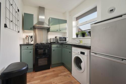 a kitchen with green cabinets and a washer and dryer at Tapton View - Modern Stay Near Chesterfield Town Center, Train Station & the Peak District in Brimington