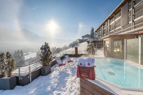 a building with a hot tub in the snow at AllgäuHotel Tanneck in Fischen