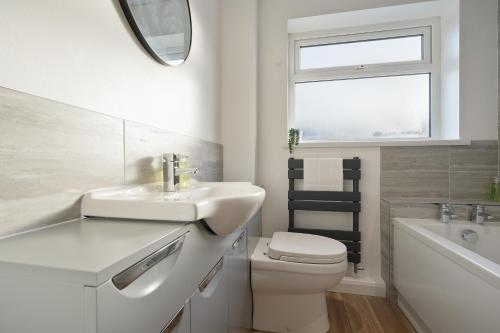 a bathroom with a sink and a toilet and a window at Tapton View - Modern Stay Near Chesterfield Town Center, Train Station & the Peak District in Brimington