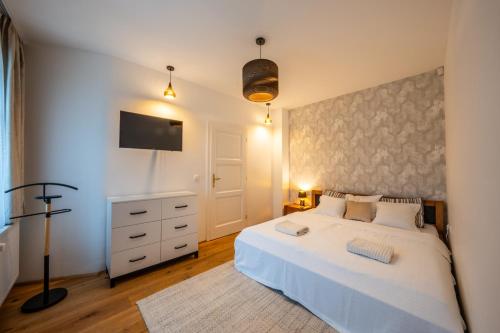 a bedroom with a white bed and a tv at Völgy Villa in Zebegény