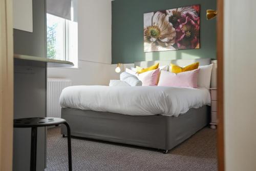 a bedroom with a bed with white sheets and colorful pillows at Tapton View - Modern Stay Near Chesterfield Town Center, Train Station & the Peak District in Brimington