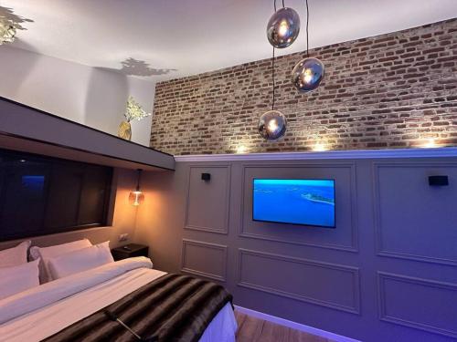 um quarto com uma cama e uma televisão numa parede de tijolos em L’Autre Nuit 