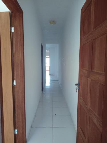 an empty hallway with a wooden door and a white floor at Casa para carnaval in Salvador