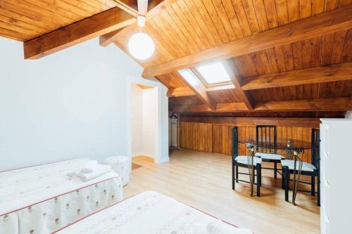 a room with a table and chairs and wooden ceilings at Chalet en la cuidad- con jardin y barbacoa in Gijón