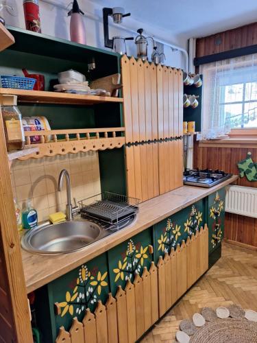una cocina con armarios de madera y fregadero en Miodowy Domek, en Kamianna