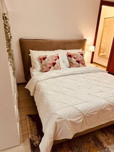 Una cama con sábanas blancas y almohadas en un dormitorio en Malu en Peschiera Borromeo