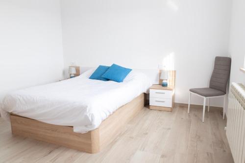 a white bedroom with a bed and a chair at Las casinas de Piedralba 