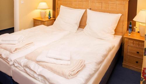 a bed with white sheets and towels on it at Apartment zum See in Ascheberg