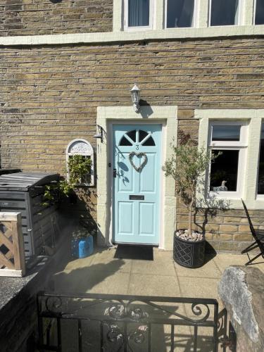 a blue door on a brick building with a bench at Cute and cosy 2 bed cottage in Honley