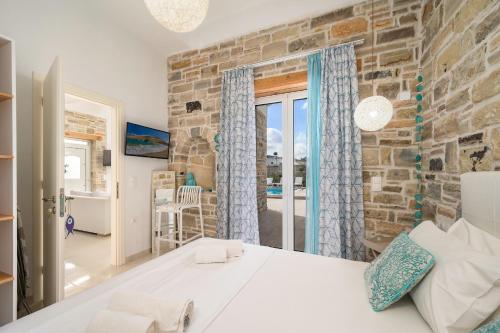a bedroom with a large bed and a stone wall at Aphrodite's Luxury Pearls 2 in Pitsidia