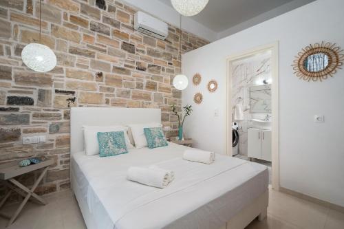 a white bed in a room with a brick wall at Aphrodite's Luxury Pearls 2 in Pitsidia