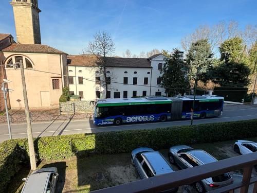 a blue bus driving down a street with parked cars at Sferica in Campalto