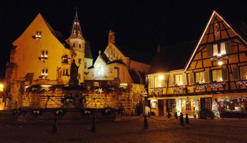 an old building with a christmas market in front of it at night at Résidence Pierre & Vacances La Petite Venise in Colmar