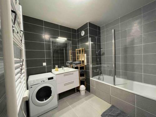 a bathroom with a washing machine and a sink and a tub at Appartement résidentiel Longjumeau in Longjumeau