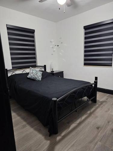 a black bed in a room with two windows at Quiet House Near the Hard R Casino and FLL Airport in Fort Lauderdale