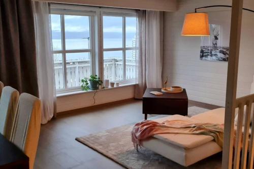 a bedroom with a bed and a table and windows at Private Mountain House with Spectacular Views in Narvik