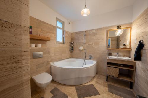 a bathroom with a tub and a toilet and a sink at Völgy Villa in Zebegény