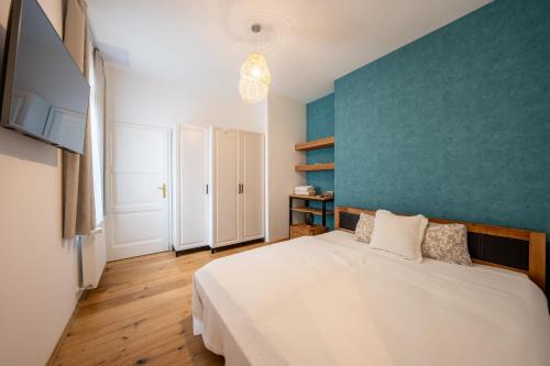 1 dormitorio con cama blanca y pared azul en Völgy Villa, en Zebegény