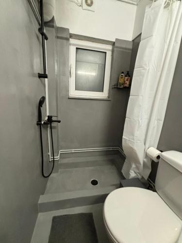 a small bathroom with a toilet and a window at Jacuzzi studio close to athens airport!! in Pallíni