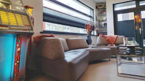 a living room with a leather couch and windows at Paradise Amsterdam bungalow of 80 m2 with private pool - All inclusive, breakfast, parking, use of bikes, tourist tax and much more in Zandvoort