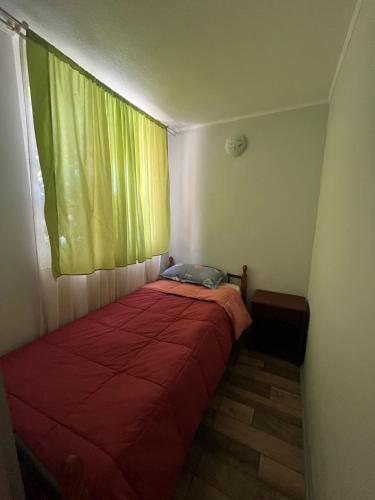 a bedroom with a red bed with a green window at Departamento Santa Beatriz,Huasco in Huasco