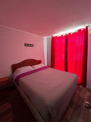a bedroom with red curtains and a bed at Departamento Santa Beatriz,Huasco in Huasco
