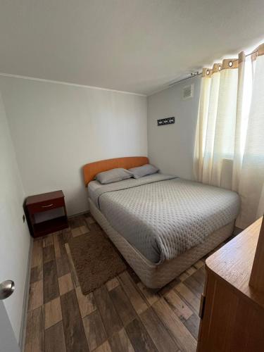 a bedroom with a bed and a wooden floor at Departamento Santa Beatriz,Huasco in Huasco