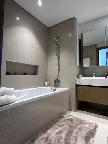 a bathroom with a tub and a sink and a mirror at Creek Harbour retreat: Luxurious 2-BR apartment in Dubai