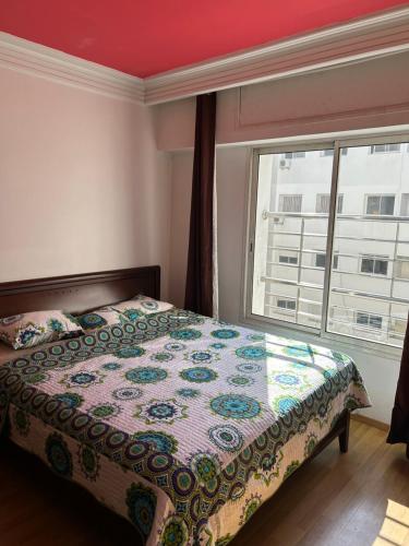 une chambre avec un lit et une grande fenêtre dans l'établissement Charmant appart 2 chamb+salon au cœur de la ville!, à Rabat