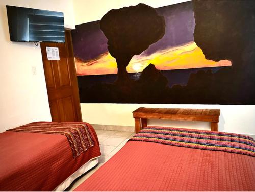a bedroom with two beds and a painting on the wall at Baja Real Hotel Boutique in La Paz
