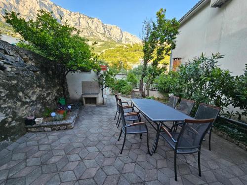 una mesa y sillas en un patio con una montaña en Studios Dolček, en Krvavica