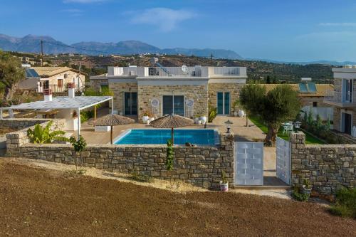 a house with a swimming pool and a stone wall at Aphrodite's Luxury Pearls 2 in Pitsidia