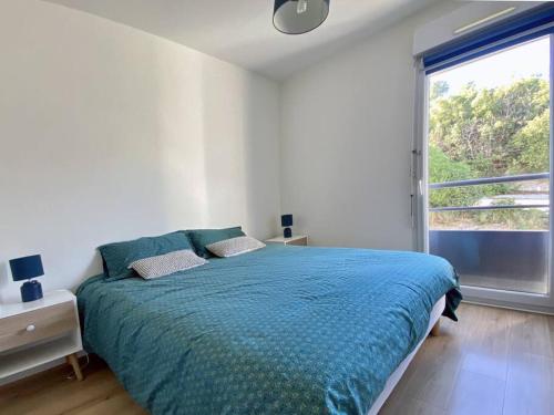 Un dormitorio con una cama azul con una ventana grande. en SEA VIEW Classé 3 étoiles climatisé Terrasse Vue Mer Parking by LaConciergerie13, en La Ciotat