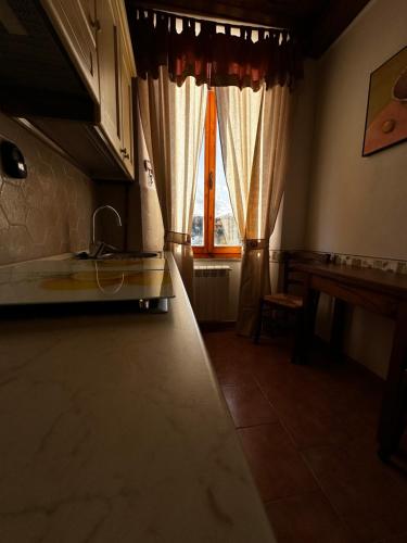 a kitchen with two windows with curtains and a table at CASA LORI - Tuscan ToBe in Santa Fiora