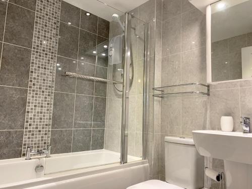 a bathroom with a shower and a toilet and a sink at Harbour Penthouse Whitby in Whitby