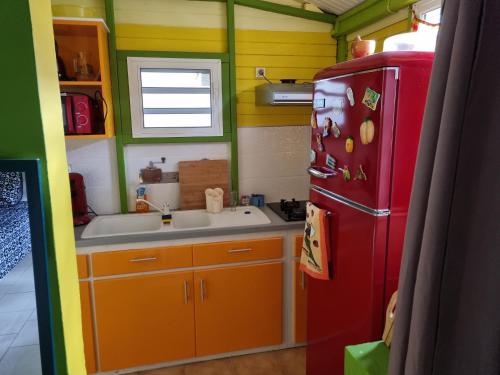 La cuisine est équipée d'un réfrigérateur rouge et d'un évier. dans l'établissement Ti kaz a Annick, à Bouillante