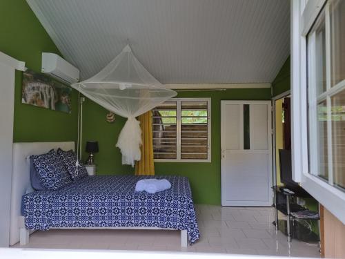 1 dormitorio con cama y pared verde en Ti kaz a Annick, en Bouillante