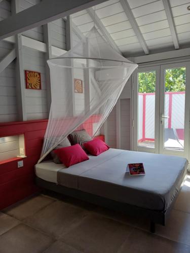 a bedroom with a bed with a mosquito net at Caraïbes Cottage Grenat piscine privée 900m de Grande anse in Deshaies