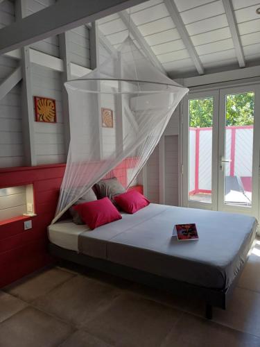 une chambre avec un lit avec moustiquaire dans l'établissement Caraïbes Cottage Grenat piscine privée 900m de Grande anse, à Deshaies