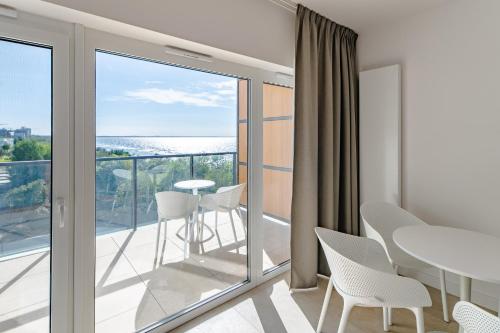 Habitación con balcón con mesa y sillas. en Aquamarina Prima Holiday Studios by the BEACH by Renters, en Międzyzdroje